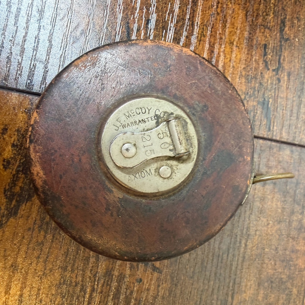 Vintage Mecoy Co. "Axiom" measuring tape housed in a leather-covered case.